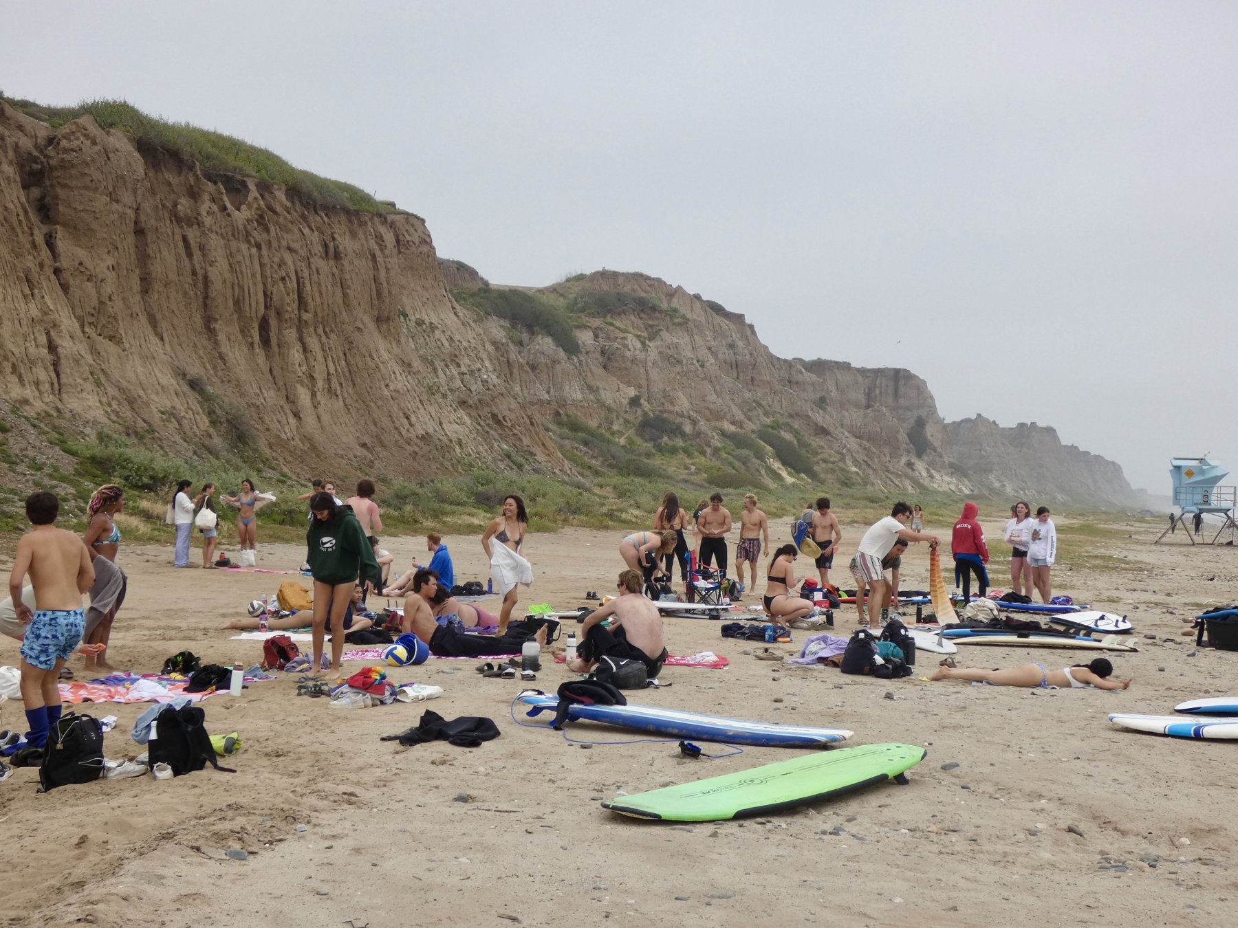 Surf club spread out on the sand below tall bluffs