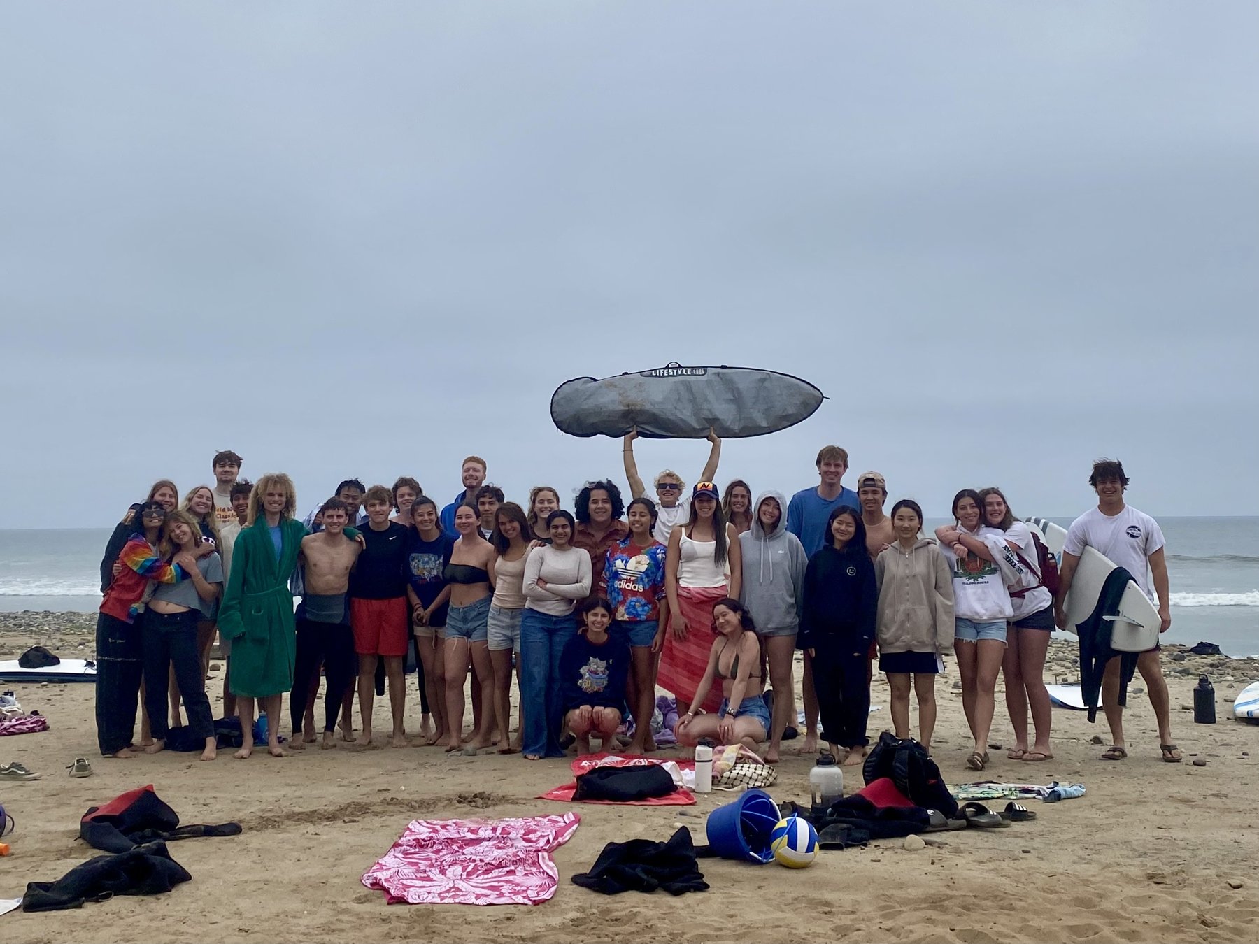 Surf club group photo on the beach, one person holding a board overhead