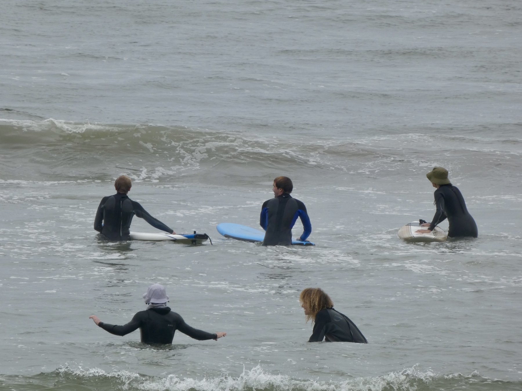 Beginners in wetsuits waiting for a wave during a lesson