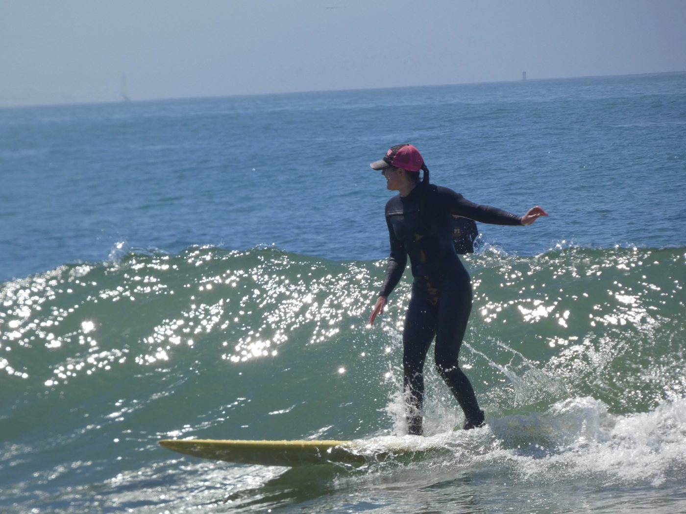 Surfer in a pink cap riding a sparkling green wave