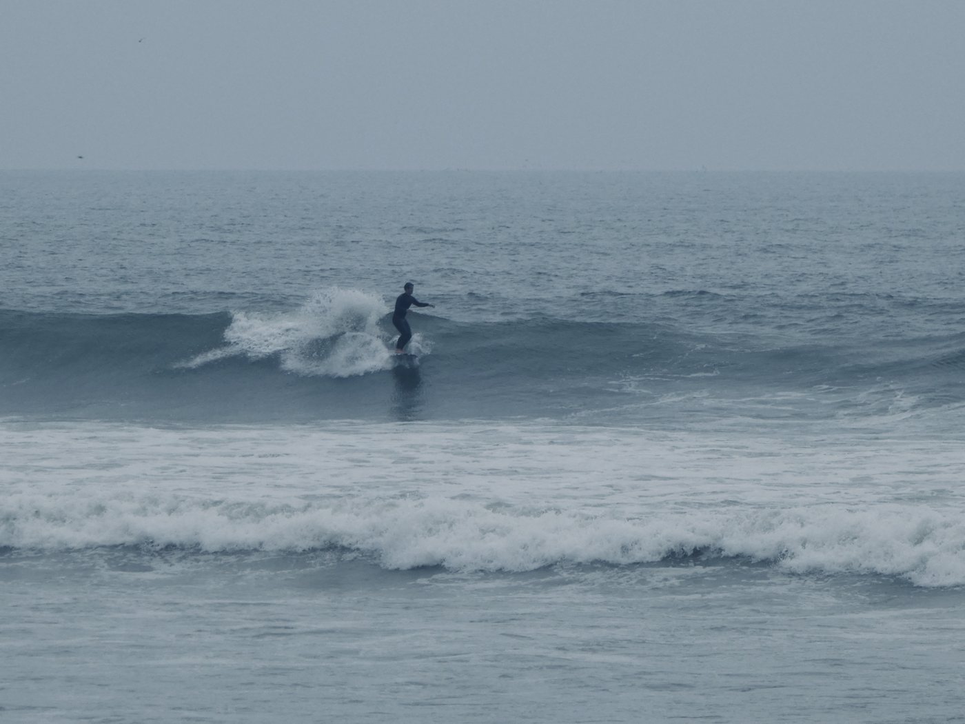 Lone surfer on a grey, misty day